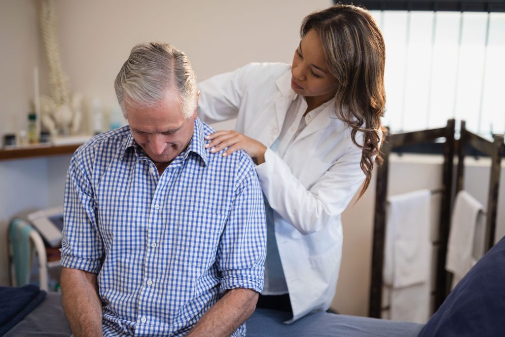 Female therapist examining neck of a patient.