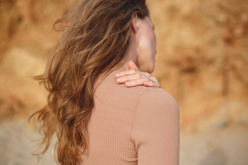 Woman in beige with shoulder pain.
